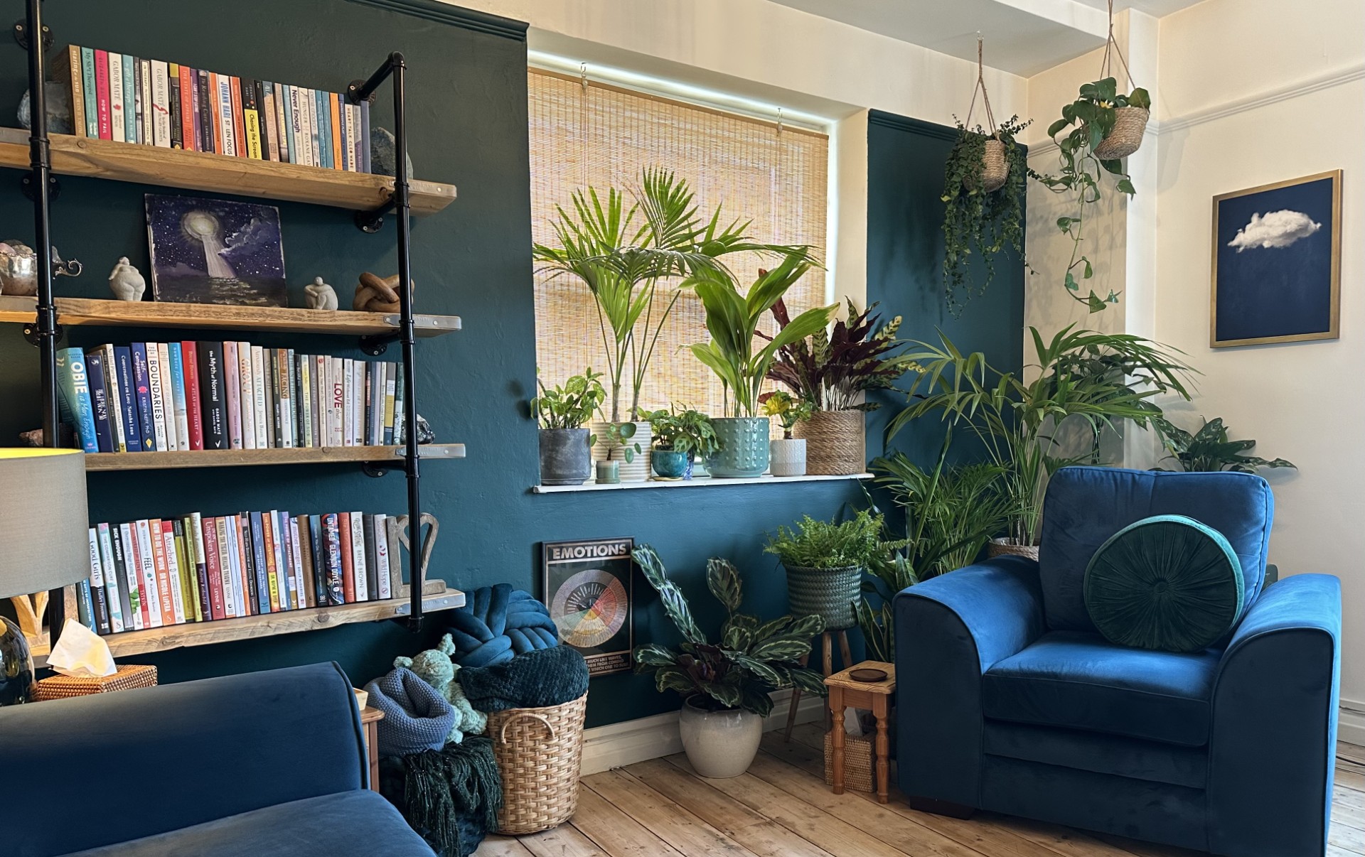 The therapy room, with bookshelves, plants, and a blue armchair